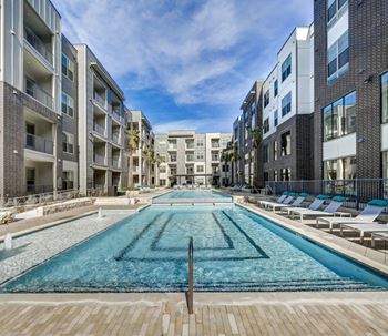 A long rectangular pool in the middle of a courtyard surrounded by buildings.